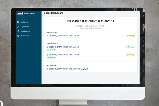 A computer monitor displays a client dashboard with agreement statuses—one pending and one complete—featuring attachments, documents, and mold inspection reports within a portal interface on a gray background.