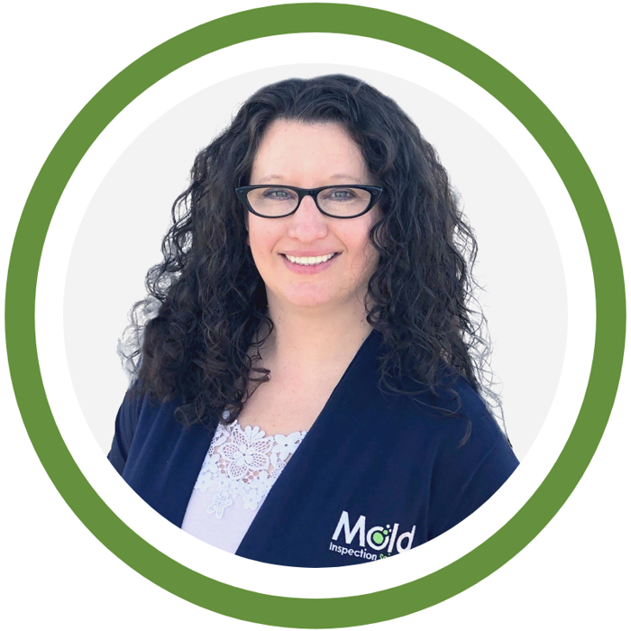 Woman with long curly black hair and glasses, wearing a dark blue jacket with a white lace top, inside a green circular frame, exuding an air of investigation.