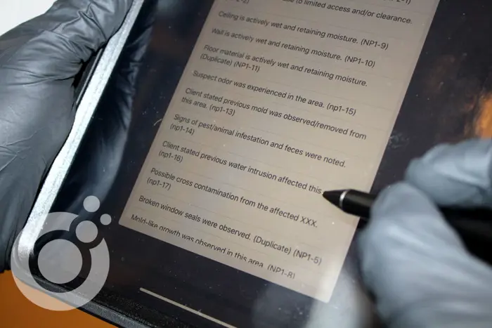 A person wearing gloves uses a stylus to review inspection notes on a tablet. The detailed inspection highlights issues like mold, pest infestation, and water intrusion that require immediate attention.