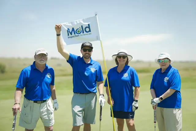 Golfers gather beside a Mold Inspection Sciences flag at Holes of Hope.